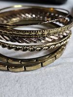 stack of eight bangles showing varied textures and gold tones