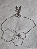 Necklace laid flat showing three hexagon pendants and thin chain