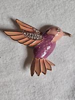 Front view of gold-tone enamel hummingbird brooch