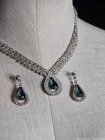 Necklace displayed on bust with earrings beside, showing overall design and scale