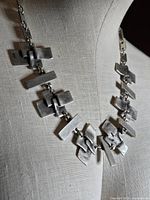 Front view of silver-plated geometric link necklace on display form