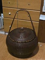 Full view of woven rattan basket showing shape, handle, and lid