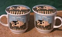 pair of ceramic tea mugs with matching lids showing pig design