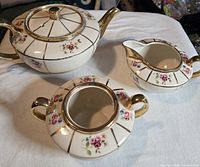 Top view of teapot, creamer and sugar bowl showing matching pattern and gold trim