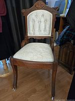 Full view of carved wood chair showing upholstery and casters