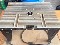 Top view of cast aluminum router table surface showing mounting openings and ribbed texture