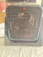 Front view of black portable space heater showing grill and red indicator light