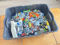 Top view of black bin filled with assorted Lego pieces in various colours and shapes