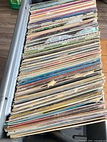 Stack of approximately 80–120 LPs in plastic crate, showing spine edges and varying sleeve colours