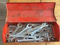 Open red metal toolbox filled with assorted combination wrenches