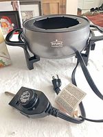 Rival electric fondue pot showing body, handles, stand, and power cord with heat control