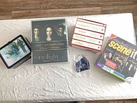 All items laid out: boxed books, two board games, tin, lanyard