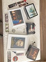 Overview of lot: framed prints, tins, T-shirt, bookmarks, pins displayed