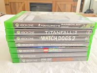 Stacked view of seven Xbox One game cases showing titles on spines