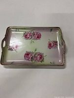 Full view of porcelain tray showing rose decoration, gold rim and side handles
