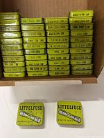 Open carton showing stacked green Littelfuse tins with specification labels