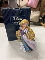 Front view of Rapunzel figurine beside Disney Showcase box