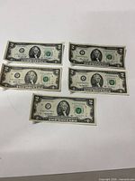 Five $2 bills laid out