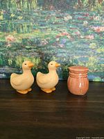 Front view of two yellow duck shakers and brown jar