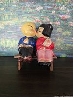 Front view of kissing couple shakers seated on bench
