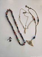 Group view of three necklaces and one clip-on earring