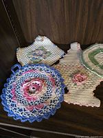 Group showing blue round, cream square, teapot shape and partial green round crochet pieces