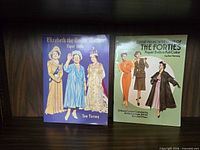 Both paper doll books standing side by side on shelf