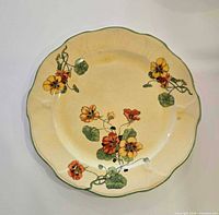 Front of scalloped ceramic dinner plate showing floral pattern and crazing