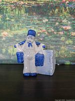 Front view of porcelain man with two buckets and attached container