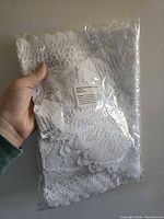 Sealed package containing folded white crochet lace dresser scarves