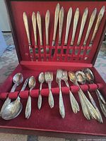Open box showing 12 knives in lid, assorted forks and spoons in base
