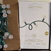 Front of box showing Wondershop branding, LED sphere light graphics, loose portion of light string visible