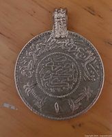 Obverse side of silver Saudi 1/2 Riyal coin pendant showing Arabic script and bail