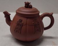 Side view showing carved panels, spout, handle and overall form