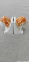 Side profile of both ceramic spaniel head bookends showing orange-tan glazed heads and white bases