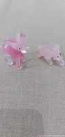 pair of pink glass elephant figurines on fabric surface