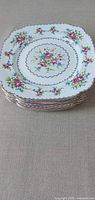 Stack of square scalloped dinner plates with floral pattern