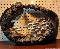 Front view showing oval resin frame and 17 silver fish inside