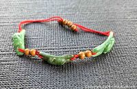 Full view of bracelet laid flat showing jade plaques, beads and red cord