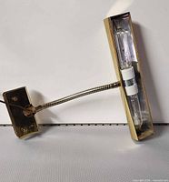 Full view of brass lamp showing mounting plate, gooseneck, and shade