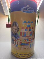 Front of Imaginarium cylindrical storage tube showing branding and sample build graphic