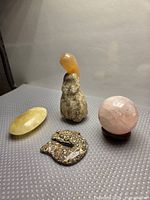 Group shot of rose quartz sphere on wood stand, yellow calcite egg, ocean jasper snake, stone figurine with carnelian cap
