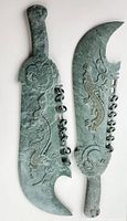Both serpentine stone swords front view showing dragon carvings and ring mounts