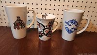 Front view of three Northwest Coast design mugs