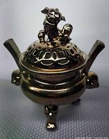 front view showing foo dog finial, pierced lid, handles, and tripod legs