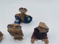 Group of four figurines showing shopping bag, closed book, burgundy coat versions