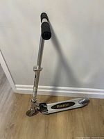 Full view of folded Razor aluminum kick scooter against wall