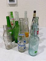 Group of assorted glass soda and beverage bottles showing variety of colors and brands