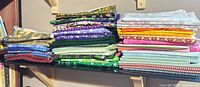 Stacked bundles of assorted cotton fabric pieces in multiple colors and patterns