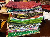 Stack of mixed print cotton fabric pieces on table